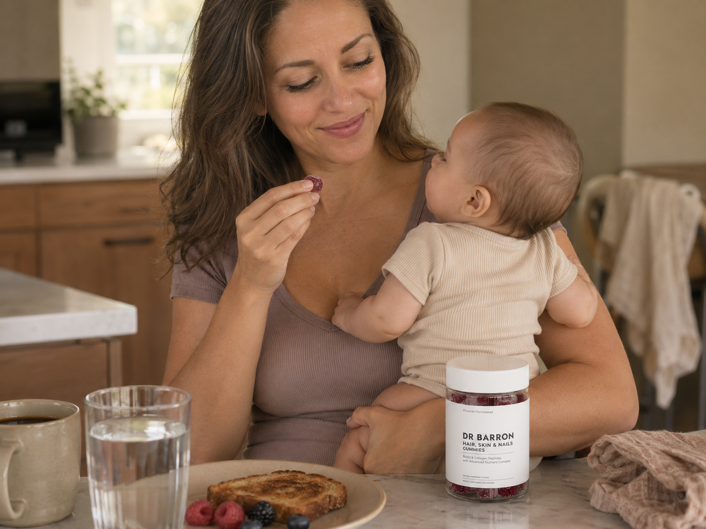 Postpartum mom holding her baby and eating a DR BARRON gummy at the kitchen counter